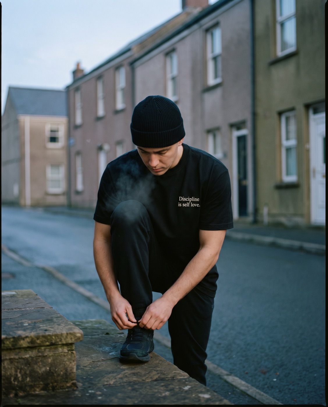 Runner tying shoes at dawn in a black tee and beanie